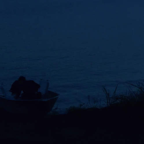 a man in a boat on the water at night
