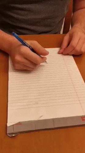 person in gloves writing on a notebook with pencil
