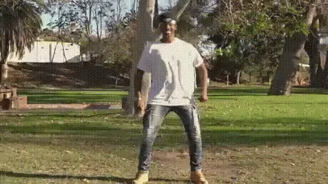 a man throwing a frisbee while standing next to a tree