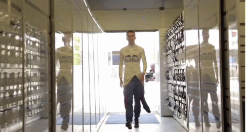 a man walks in a hallway of glass and metal