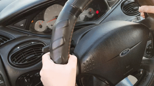 a car steering wheel being driven on by a gloved hand