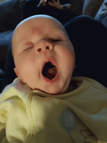 a baby yawns in the light of an electric toothbrush