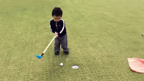 the little boy is practicing his golf ss