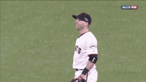 the baseball player stands in the rain, in his uniform