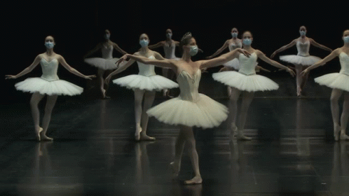 a line of ballet dancers in white tutus with one dancing in the center of their body