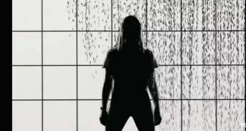 a person stands in front of some rain pouring on the wall