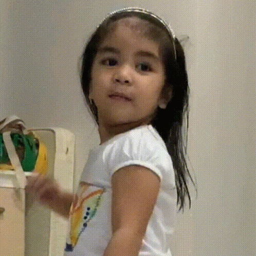 a little girl holding a water bottle near a refrigerator
