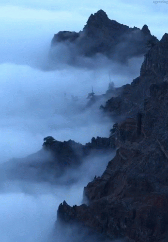 an airplane flying over a foggy mountain range