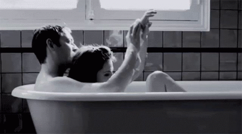 a man and woman sit inside of a bathtub