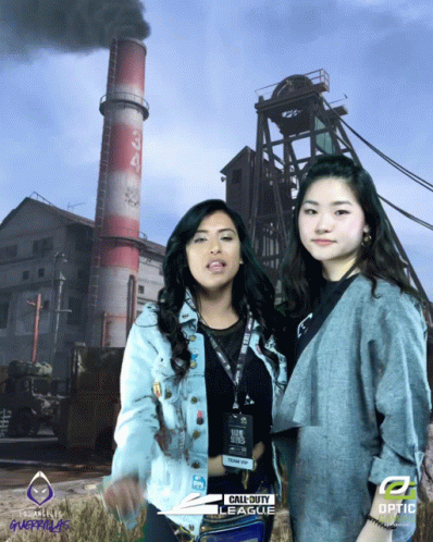 two women stand by a train, with smoke billowing out of the stacks