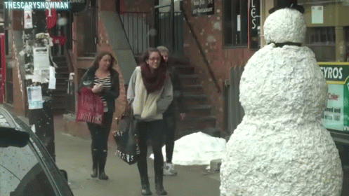 two girls standing in front of a snowman