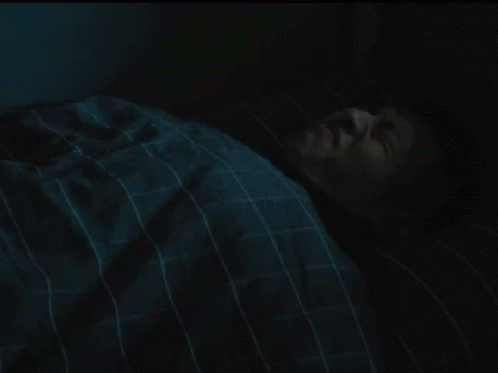 a person asleep on a bed in the dark