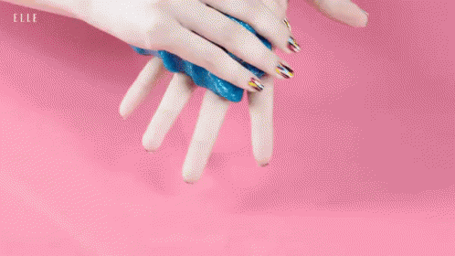 womans hands with gold and blue manicured nails holding soing in one arm