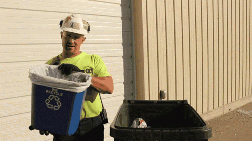 a man in a hardhat holding a trash can