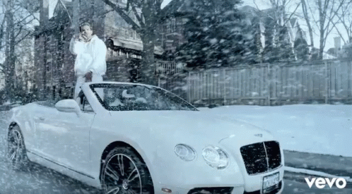 a man is riding on the hood of a white car