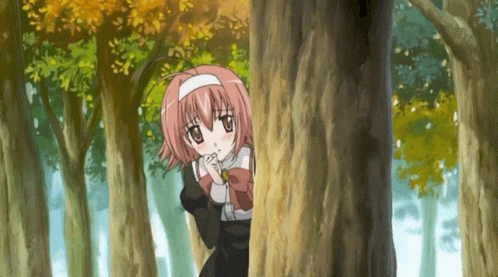 a girl is standing behind a large tree in the woods