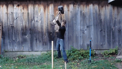 a person in brown pants is spraying paint on a wooden wall