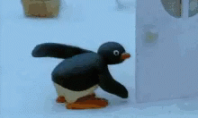 the small toy penguin is standing near the refrigerator