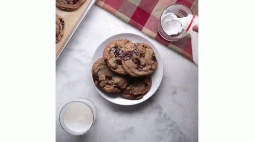 a plate with cookies on a table next to a glass of milk
