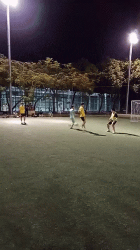 people playing soccer on the field at night