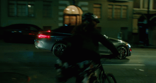 blurry pograph of a man riding his bike on a dark street