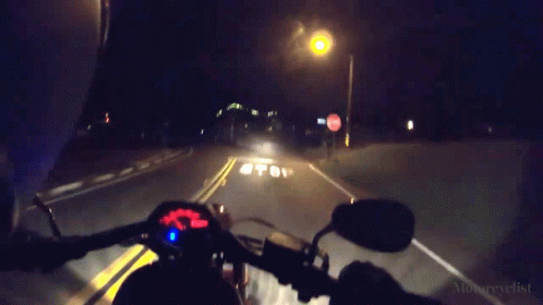 a motorcycle traveling down a dark road at night