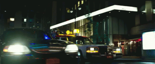 two police cars driving through the street at night