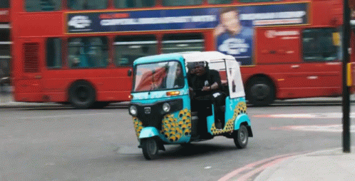 a yellow and blue tuk - tuks is driving down the street