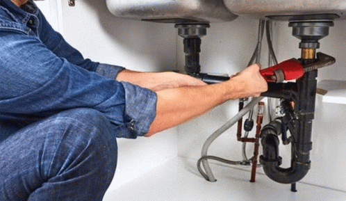a plumber kneels down to the ground next to a drain