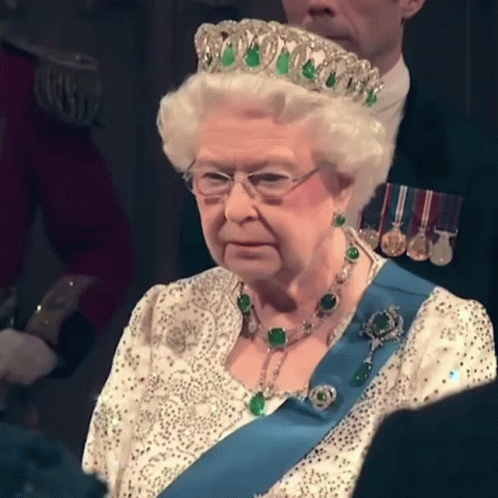 a queen sitting down wearing a tiara