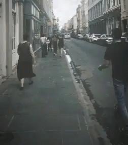 a couple of men walk on the sidewalk