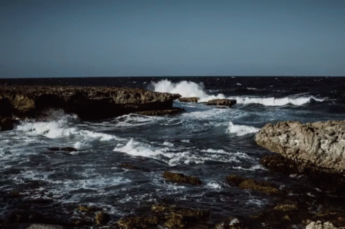 there is a large wave crashing on a rocky shore