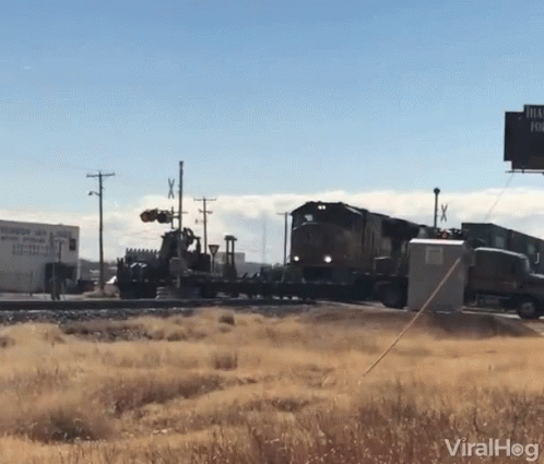 two trains traveling down tracks next to a road