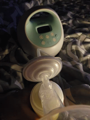 a baby bottle is on the bed next to an alarm clock
