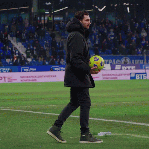 a man standing on a soccer field holding a ball