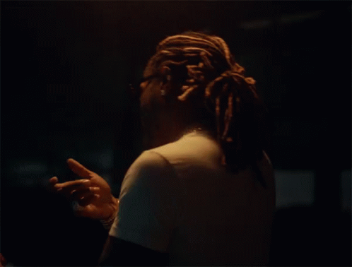 a person standing in the dark with dread locks