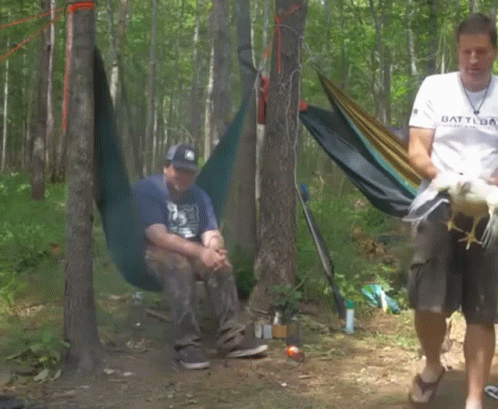two people in a wooded area are camping