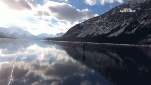 man standing on shoreline in front of mountain