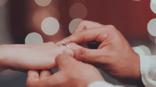 two people who are holding hands while they hold rings