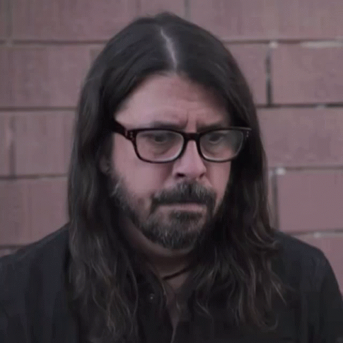 the bearded man is wearing glasses and long hair