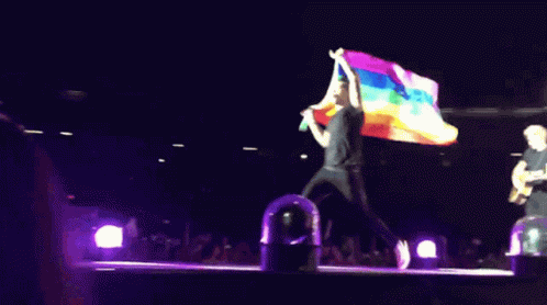 the man is carrying the gay flag on stage
