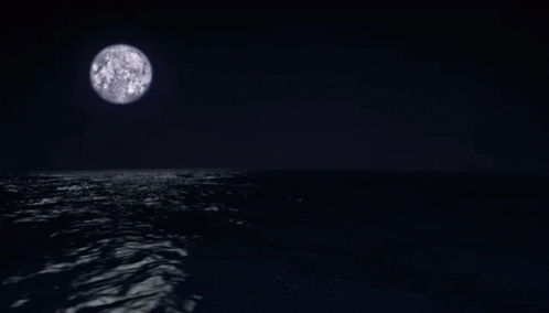 the moon on the horizon of the ocean at night
