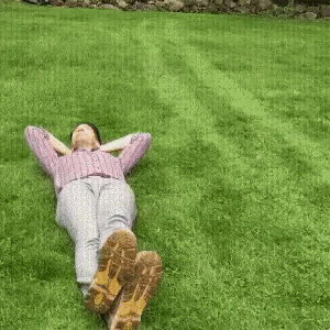 a person laying on the grass with their hands in their pockets