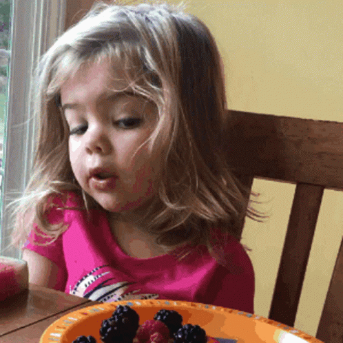 little girl looking at plate with donuts on a plate