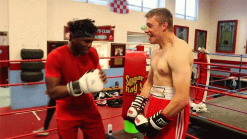 one male boxer is boxing while another male looks on