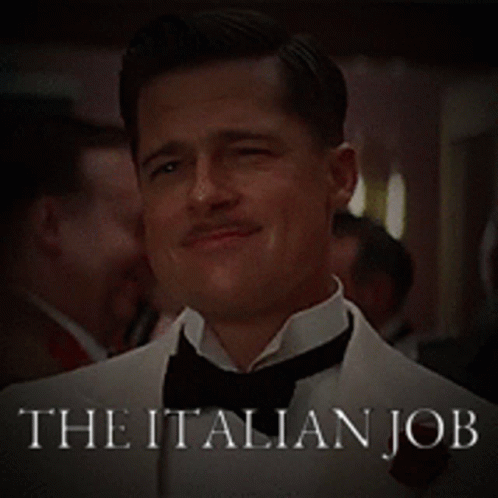 a smiling man in a suit and tie is appearing in the italian job