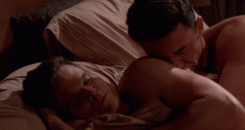 a couple in bed and the male is touching his shoulder