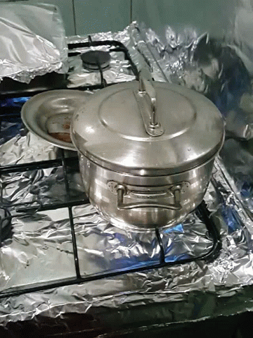 an open pot on top of a stove wrapped in foil