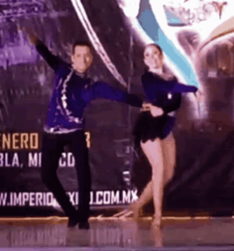 two people doing dances on stage with advertit in the background