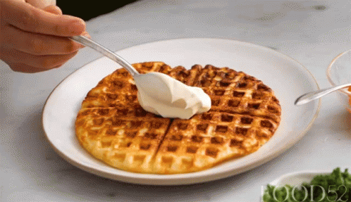 someone wearing gloves is painting the top of waffles